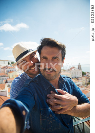Pleased gay couple making selfie on balcony Pleased gay couple making selfie on balcony 83103362