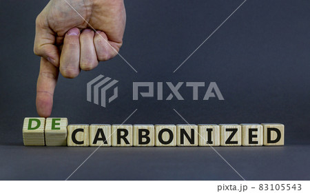 Carbonized or decarbonized symbol. Businessman turns wooden cubes and changes words 'carbonized' to 'decarbonized'. Grey background, copy space. Business, Carbonized or decarbonized concept. Carbonized or decarbonized symbol. Businessman turns wooden cubes and changes words 'carbonized' to 'decarbonized'. Grey background, copy space. Business, Carbonized or decarbonized concept. 83105543