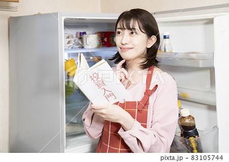 冷蔵庫を開けたまま投資のことを考える女性 83105744