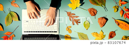 Autumn leaves with person using a laptop computer Autumn leaves with person using a laptop computer 83107674