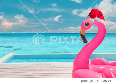 Christmas beach summer vacation flamingo pool float with santa hat travel background for winter holidays 83108341
