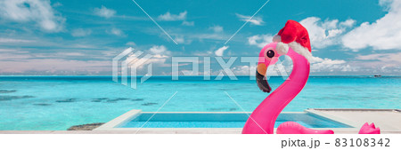 Christmas travel holidays beach destination banner funny pool flamingo with Santa hat at luxury south winter destination during Xmas. Landscape header background 83108342