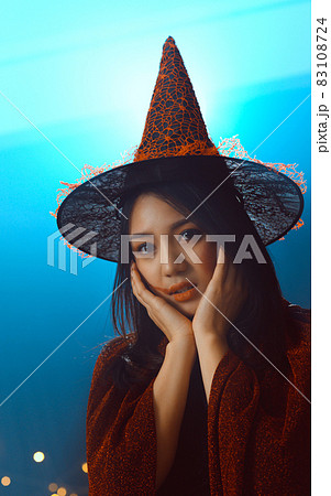 Portrait of beautiful young woman in witch halloween costume wear witches hat holding broom over spooky dark magic background - Halloween party art design. 83108724