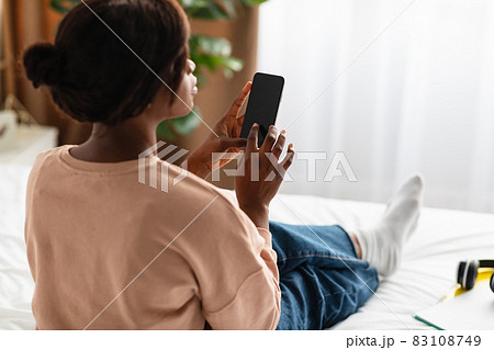 Back-View Of Black Lady Using Phone With Blank Screen Indoor Back-View Of Black Lady Using Phone With Blank Screen Indoor 83108749