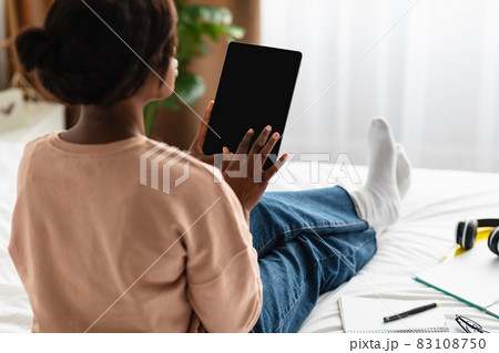 Black Woman Using Digital Tablet With Empty Screen Indoor, Rear-View Black Woman Using Digital Tablet With Empty Screen Indoor, Rear-View 83108750
