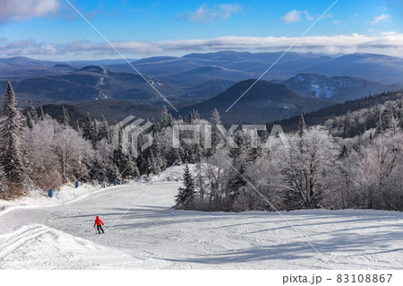 Ski slope mountain scenery lansdcape with lonelys skier skiing downhill on first tracks fresh snow alone with frozen treeline. Winter sport resort, people skiing at Mont-Tremblant, Quebec, Canada 83108867
