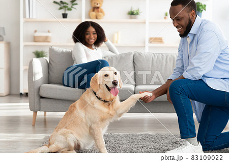 Smiling black man teaching dog to give paw 83109022