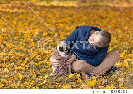 A man with his beloved pug dog on a walk in the autumn in the park 83109839