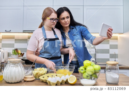 Mom and teenage daughter preparing apple pie together Mom and teenage daughter preparing apple pie together 83112069