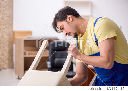 Young male carpenter repairing chair in the office Young male carpenter repairing chair in the office 83112115