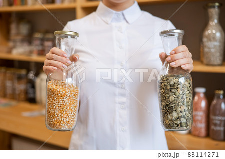 A woman holds two jars of cereals. Eco shop. 83114271