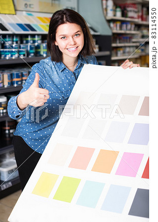 smiling female customer examining color scheme variants in paint store smiling female customer examining color scheme variants in paint store 83114550