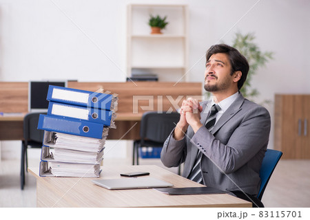 Young male employee unhappy with excessive work in the office 83115701
