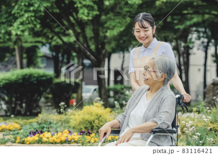 車椅子に乗った高齢者女性と女性スタッフ（花畑） 83116421