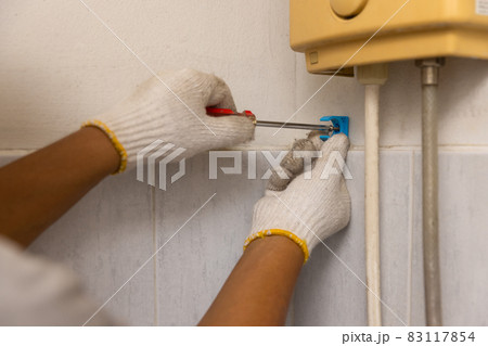 Worker installing floating pipeline on the wall in the old bathroom Worker installing floating pipeline on the wall in the old bathroom 83117854