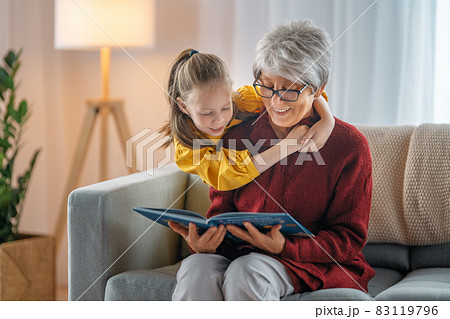 Grandmother reading a book to granddaughter. 83119796