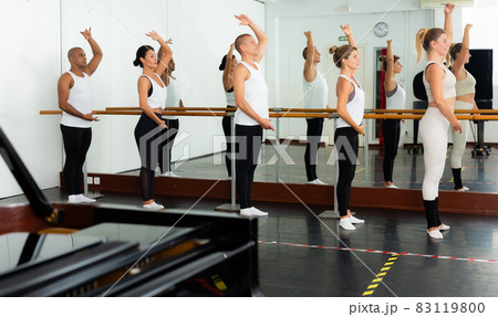 Dancers doing exercises on stretching ballet barre Dancers doing exercises on stretching ballet barre 83119800