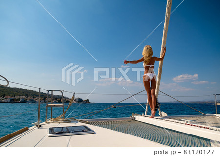 Woman in bikini tanning and relaxing on a summer catamaran sailing cruise 83120127