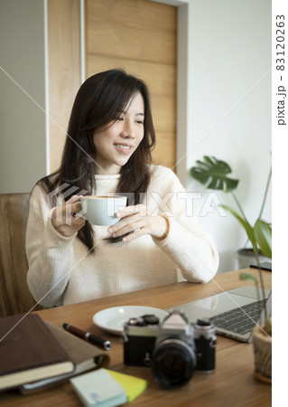 Portrait of smiling young woman in sweater sitting in office room and drinking hot coffee. Portrait of smiling young woman in sweater sitting in office room and drinking hot coffee. 83120263