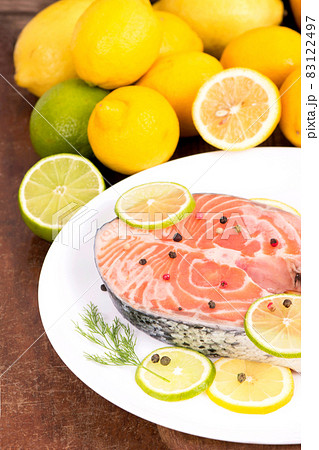 Steak of red fish and sliced lemons on wooden table 83122497