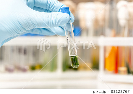 Scientist fingers holding a glass test tube in a research lab Scientist fingers holding a glass test tube in a research lab 83122767
