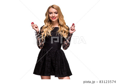 Beautiful blonde in a black dress with casino chips in hands isolated on a white background 83123574