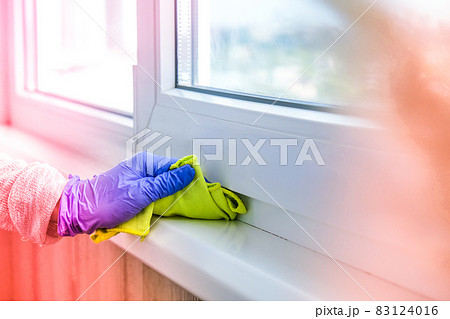Cleaning the windowsill wiping dust by blue microfiber cloth for cleaning on the glass window rail Blue Gloves Cleaning Using Sprayed Liquid. Housework and housekeeping concept. Spring 83124016