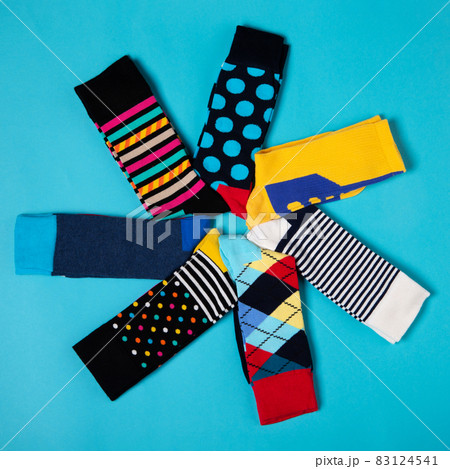 seven pairs of colored socks with different patterns, laid out in a circle, in the shape of a flower, on a cyan background, lifestyle concept 83124541