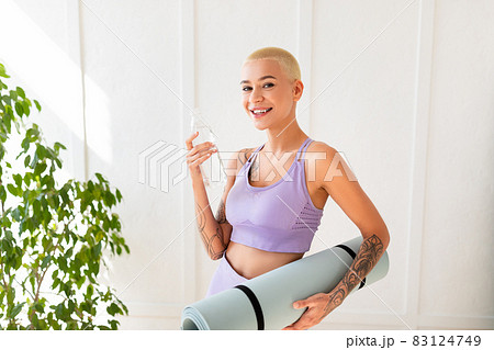 Fitness day. Young fit lady in sportswear holding yoga mat and water in bottle, ready for sport training Fitness day. Young fit lady in sportswear holding yoga mat and water in bottle, ready for sport training 83124749
