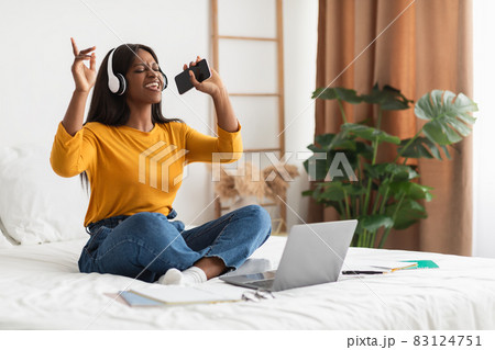 African Lady Listening To Music Wearing Headphones Singing In Bedroom 83124751
