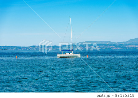 Sailing Boat Moored in front of the Coast of Lake Garda - Lazise village Veneto Italy 83125219