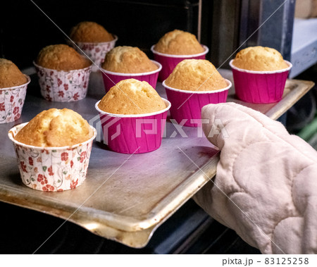 Woman baking cupcakes in the oven 83125258