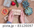 Christmas Gift box wrapped in craft paper in hands of woman 83126097