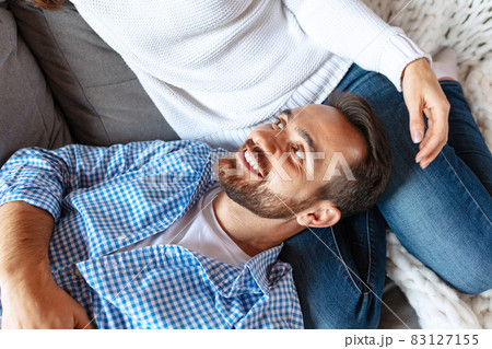 Happy married couple spending time together at home, indoors. Young man and woman sitting on sofa. Concept of family, relationship 83127155