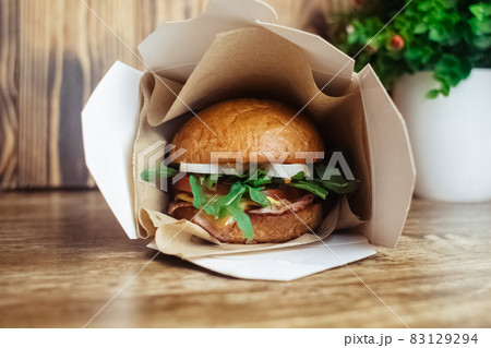 Close-up of a standard burger. Adult fast food in a restaurant or cafe. Macro photo of burger ingredients with meat, cheese and herbs. Eco burgers for the whole family 83129294