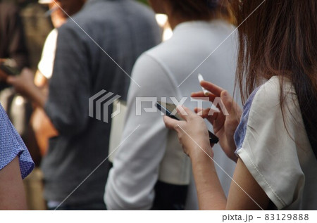 タバコを持ったままスマートフォンを操作する女性 83129888