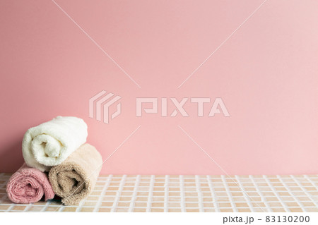 Bathroom towel on mosaic tile table. pink wall background. Skin care and spa concept. Home interior 83130200