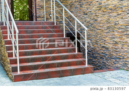 modern staircase with handrails and steps to the entrance to the building, decorative stone wall and lantern 83130597