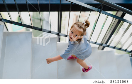 High angle view of little girl walking up the stairs indoors. 83131663