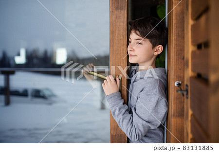 Preteen girl looking standing in open door looking out at snowy nature 83131885