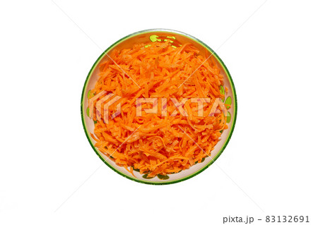 Shredded fresh carrots in a bowl on a white background. Vegetable carrot salad in a green plate. 83132691