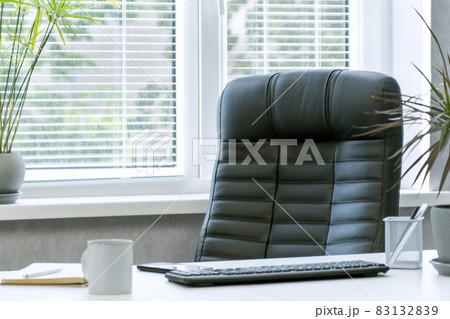 Bright office. Comfortable workplace. Leather chair. Keyboard, notebook and cup of coffee on the desktop. Bright office. Comfortable workplace. Leather chair. Keyboard, notebook and cup of coffee on the desktop. 83132839