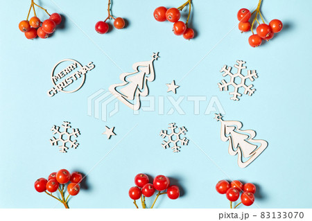 Wooden figurines of snowflakes and Christmas trees on a blue background decorated with rowan berries 83133070