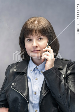 Portrait of stylish young woman in leather jacket with phone in her hands. Vertical frame. Portrait of stylish young woman in leather jacket with phone in her hands. Vertical frame. 83134271