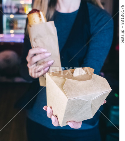 Food delivery. The girl holds paper bags with fast food in her hands. The concept of countering covid 19. Delivery from a restaurant or cafe. Unpacking meal containers 83136176