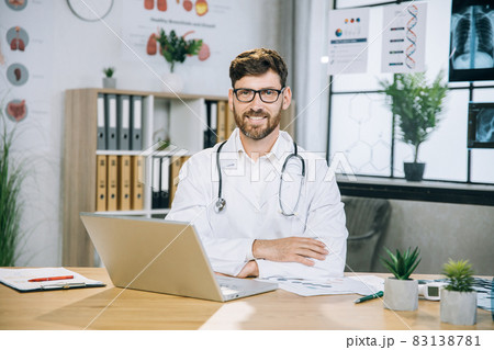 Caucasian doctor sitting at desk and smiling on camera 83138781