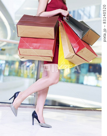young woman carrying colorful paper bags walking in shopping mall 83140520