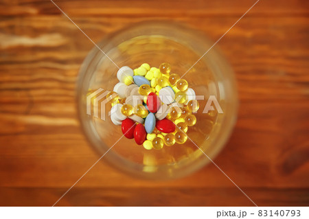Flat lay of glass with colorful vitamins and pills inside. 83140793