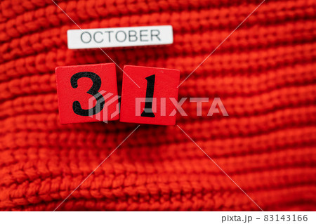 Wooden cube calendar showing October 31, Halloween isolated on red background red knitted sweater. Wooden cube calendar showing October 31, Halloween isolated on red background red knitted sweater. 83143166