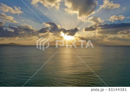 沖縄の海に沈む夕陽・夕焼けをドローンで空撮  83144381